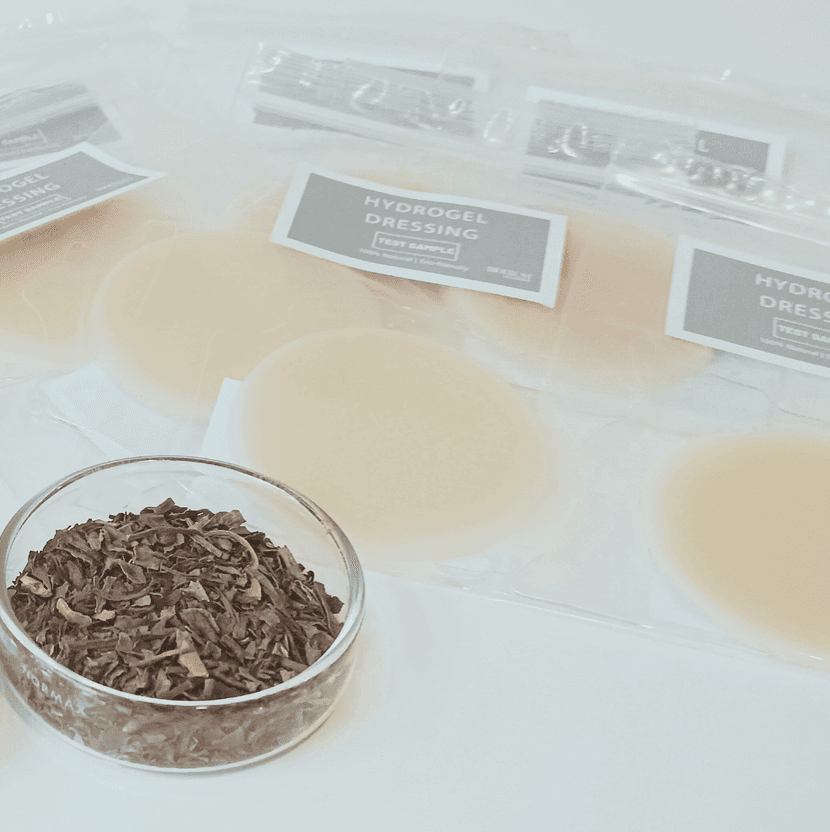 Ervas secas em recipiente de vidro junto a amostras circulares de curativos de hidrogel.
